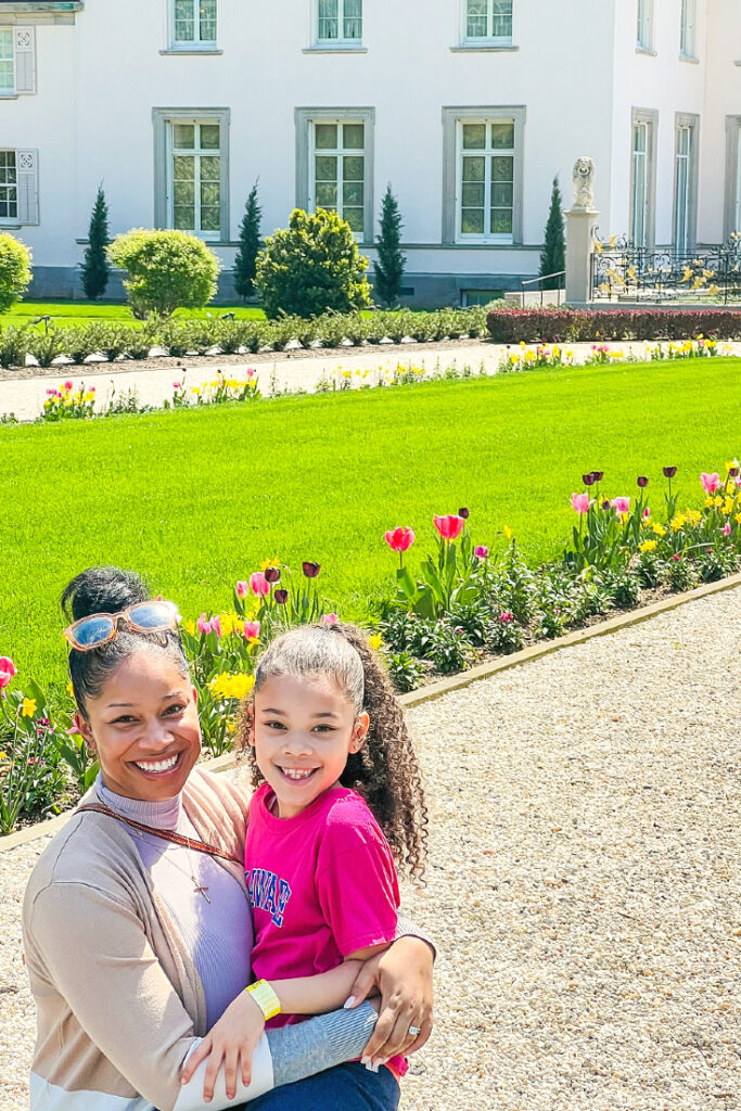 victoria vaden next to daughter in front of large mansion and front yard